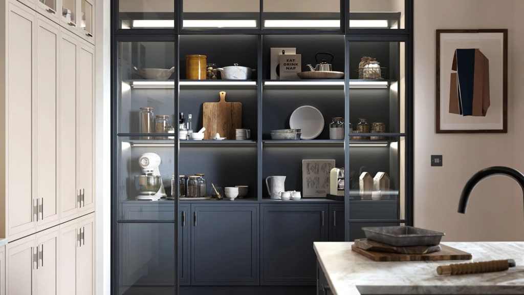 The Arrington dark blue pantry in a kitchen showcasing kitchenware on the shelves.